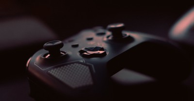 A close-up shot of a game controller in low light, highlighting its design and buttons.