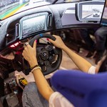 Person using a realistic VR racing simulator at a gaming event, focused on the immersive experience.