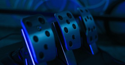 Detailed shot of gaming pedals illuminated by blue light, perfect for racing simulation setups.