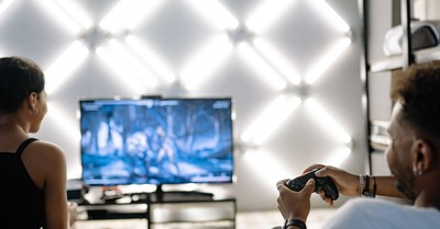 Two adults are having fun playing video games in a stylish, modern living room with LED lighting.