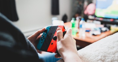 Crop unrecognizable person using console in hands while playing videogame on blurred background