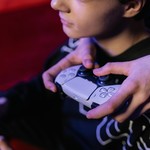 Close-up of teenagers playing video games together using modern game controllers.